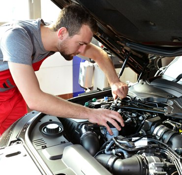 KFZ Mechaniker Repariert Motor Eines Fahrzeugs In Der Autowerkstatt Car Mechanic Repairs Engine Of A Vehicle In The Garage (1)