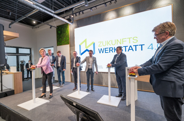 Wirtschaftsministerin Dr. Nicole Hoffmeister-Kraut in einem rosa Blazer eröffnet gemeinsam mit anderen Beteiligten im Anzug die Zukunftswerkstatt 4.0. mit einem Buzzer. Im Hintergrund eine Leinwand mit einem Schriftzug zur Zukunftswerkstatt.