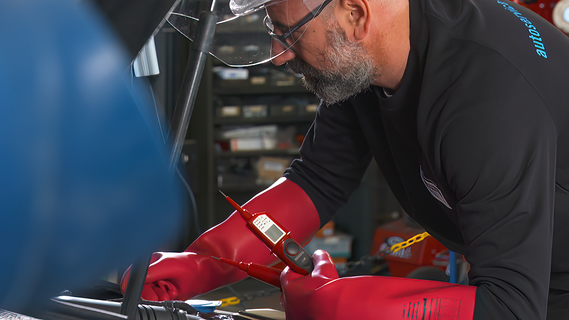 Zur Arbeit an Elektroautos müssen Werkstattmitarbeiter die richtige Schutzkleidung tragen, beispielsweise Isolierhandschuhe und Gesichtsvisier.
