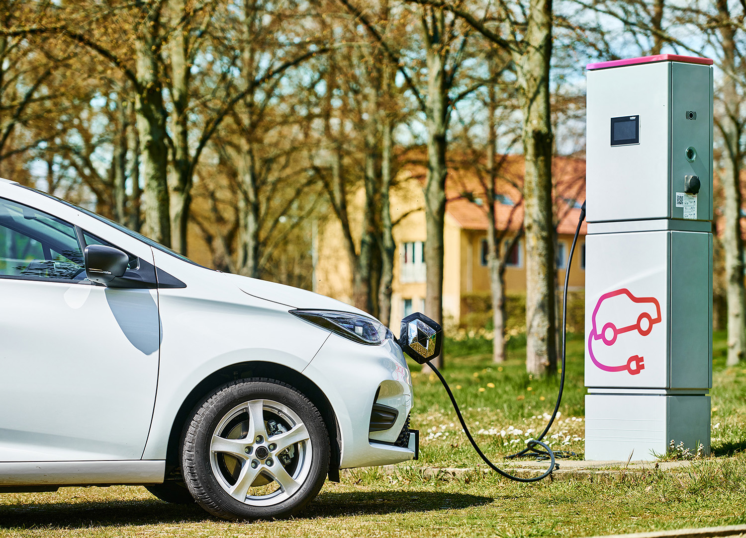 Elektrofahrzeug der Marke Renault befindet sich an einer Ladestation im Grünen.